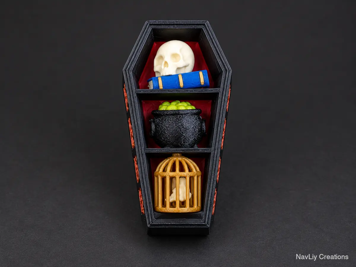 Three-compartment coffin organizer arranged with a skull and book, cauldron, and golden birdcage